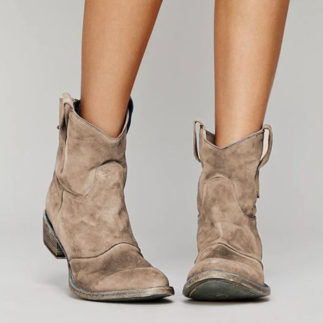 Beigefarbene Damen-Western-Stiefeletten in Wildleder-Optik mit niedrigem Blockabsatz und praktischen Anziehlaschen.