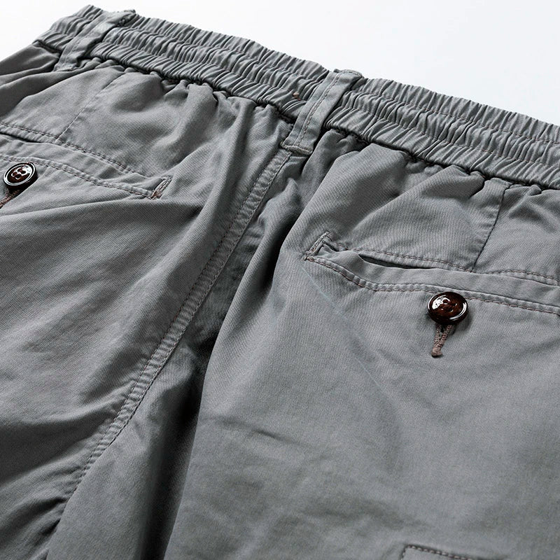Graue Herren-Cargoshorts mit elastischem Bund, Kordelzug und zwei geknöpften Gesäßtaschen aus robustem Baumwollstoff.