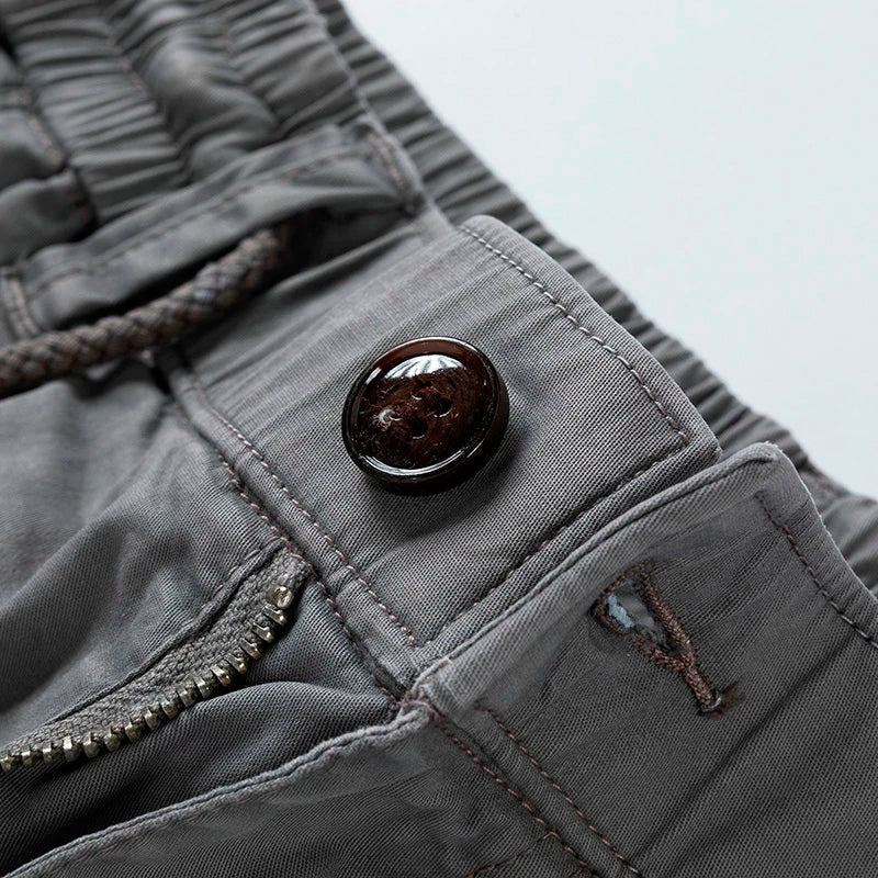 Graue Herren-Cargoshorts mit elastischem Kordelzugbund, Reißverschluss und dunklem Knopfdetail.
