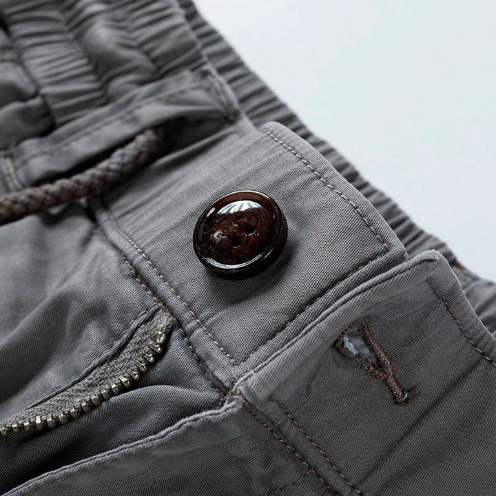 Graue Herren-Cargoshorts mit elastischem Kordelzugbund, Reißverschluss und dunklem Knopfdetail.