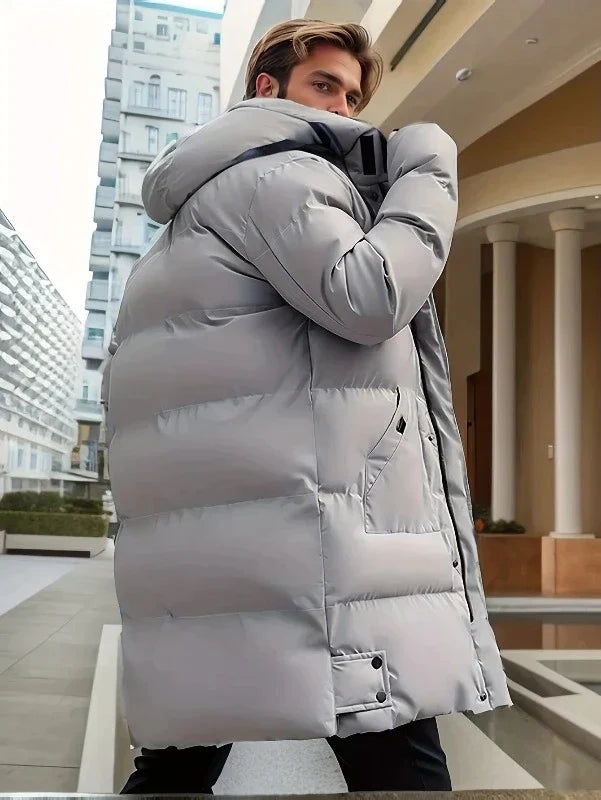 Lange, hellgraue Herren-Pufferjacke mit Kapuze, gesteppter Wattierung und praktischen Taschen für den Winter.