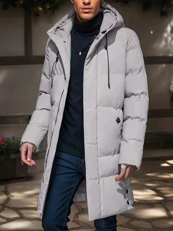 Lange, hellgraue Herren-Pufferjacke mit Kapuze, gesteppter Wattierung und praktischen Taschen für den Winter.