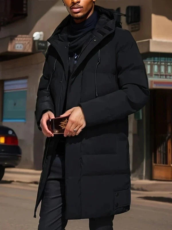 Schwarze, lange Herren-Pufferjacke mit Kapuze, gesteppter Wattierung und praktischen Taschen für den Winter.