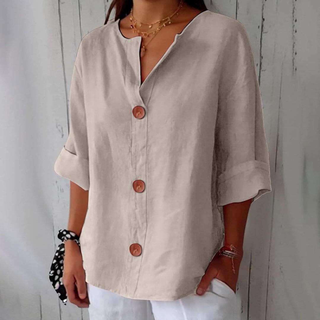 Beige Leinenbluse mit V-Ausschnitt, 3/4-Ärmeln und großen braunen Knöpfen in lockerer Passform.
