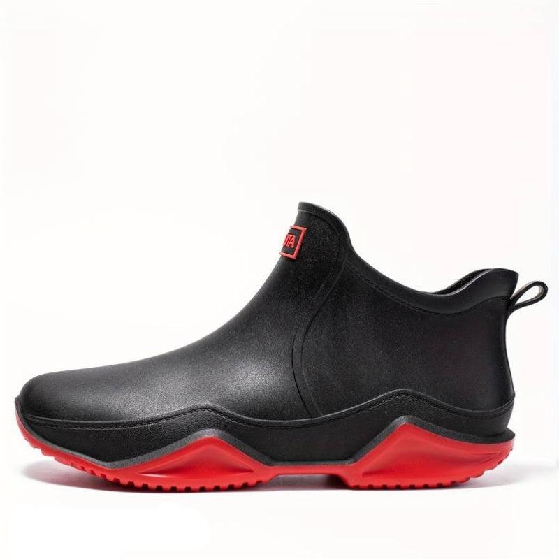 Schwarze, wasserdichte Damen-Stiefeletten zum Schlüpfen mit markanter roter Wellen-Laufsohle und Zuglasche.