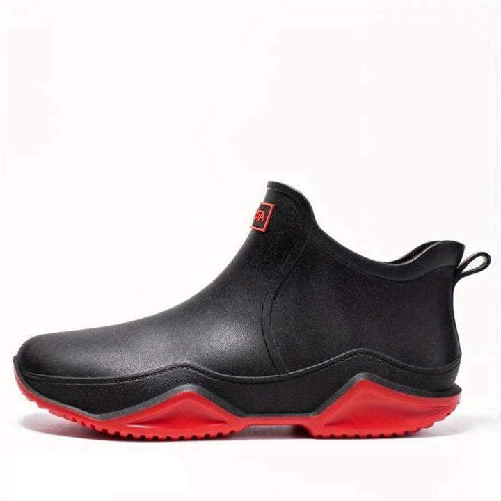 Schwarze, wasserdichte Damen-Stiefeletten zum Schlüpfen mit markanter roter Wellen-Laufsohle und Zuglasche.