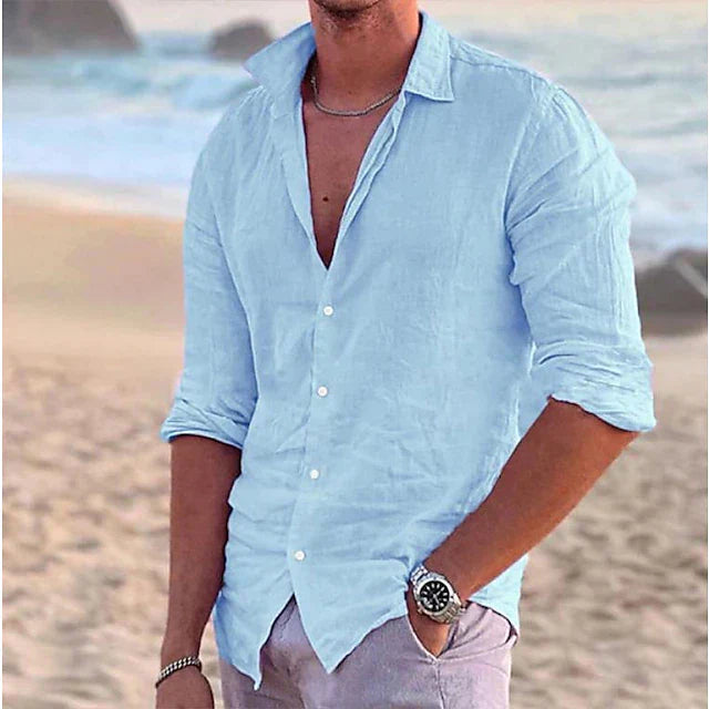Hellblaues Herren-Leinenhemd mit langem Arm, klassischem Kragen und Knopfleiste am Strand.