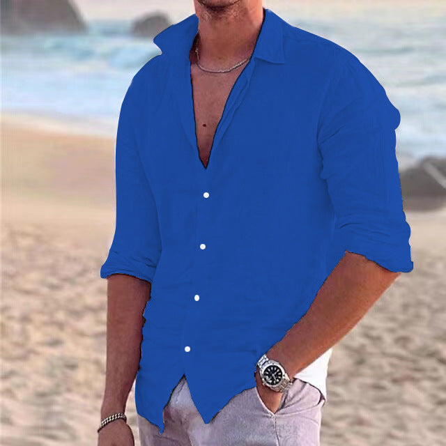 Blaues Herren-Langarmhemd aus Baumwoll-Leinen-Mix mit klassischem Kragen und Knopfleiste vor einer Strandkulisse.