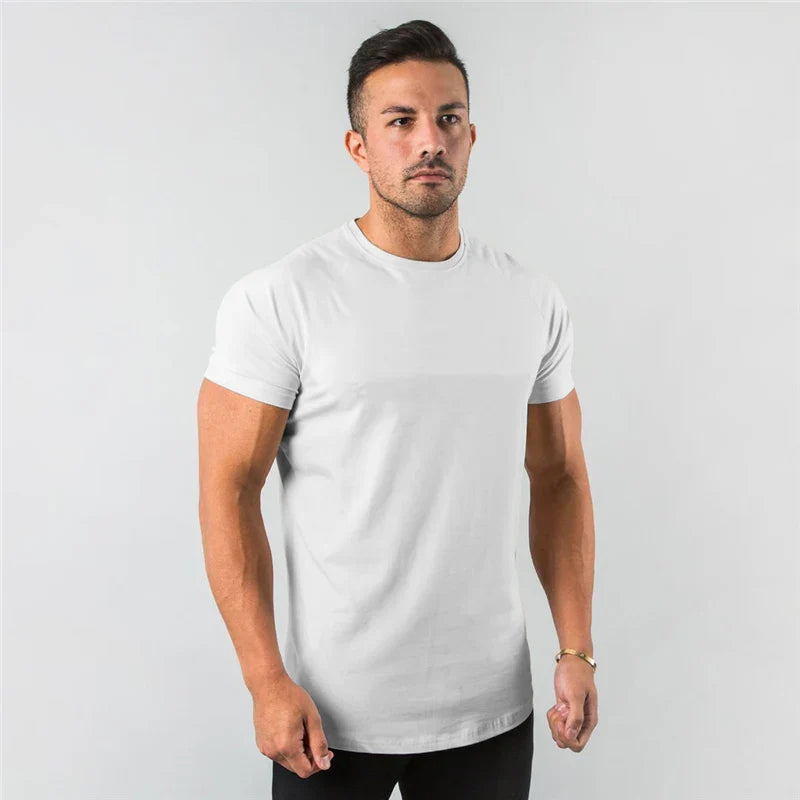 Muskulöser Mann trägt ein weißes, figurbetontes Marco T-Shirt mit kurzen Ärmeln und Rundhalsausschnitt vor grauem Hintergrund.