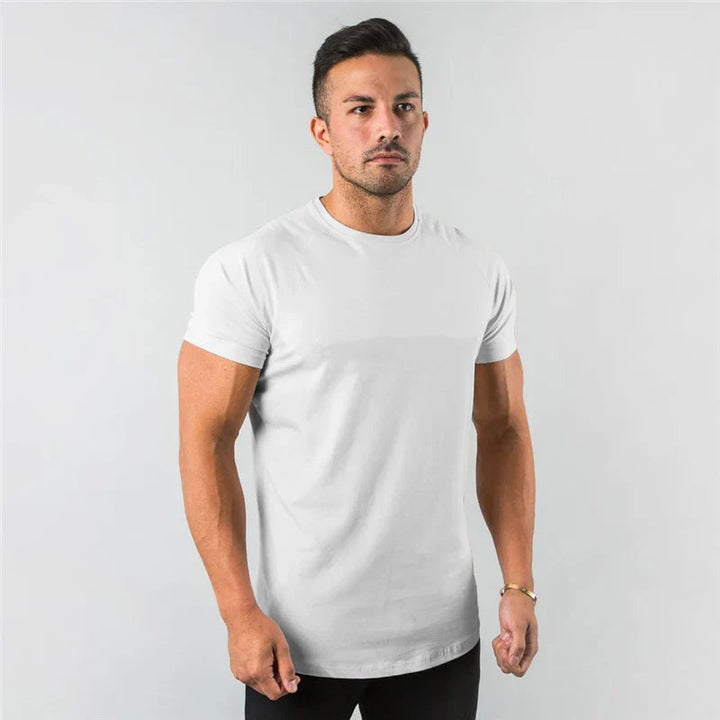 Muskulöser Mann trägt ein weißes, figurbetontes Marco T-Shirt mit kurzen Ärmeln und Rundhalsausschnitt vor grauem Hintergrund.