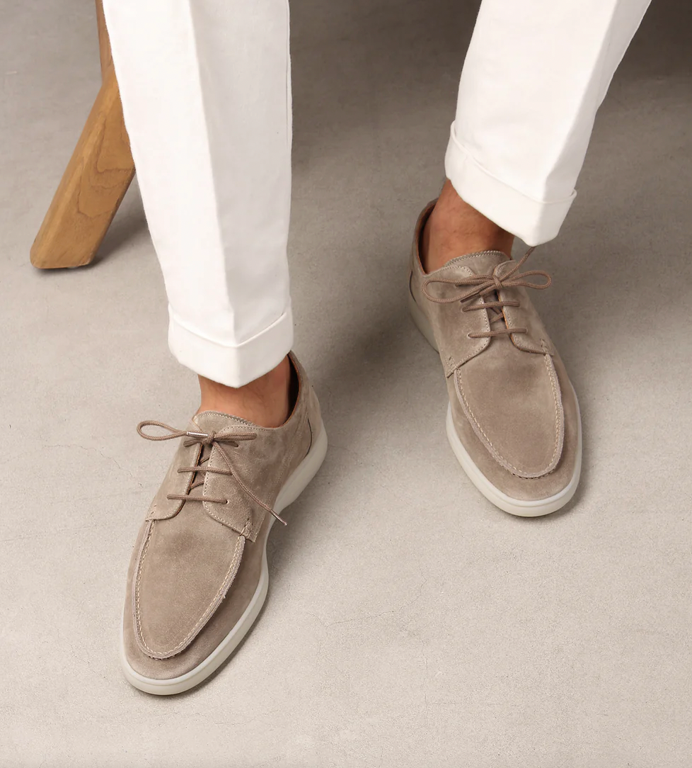 Beigefarbene Marco Herren-Schnürschuhe aus weichem Wildleder mit heller Sohle und klassischer Schnürung zu weißer Hose.
