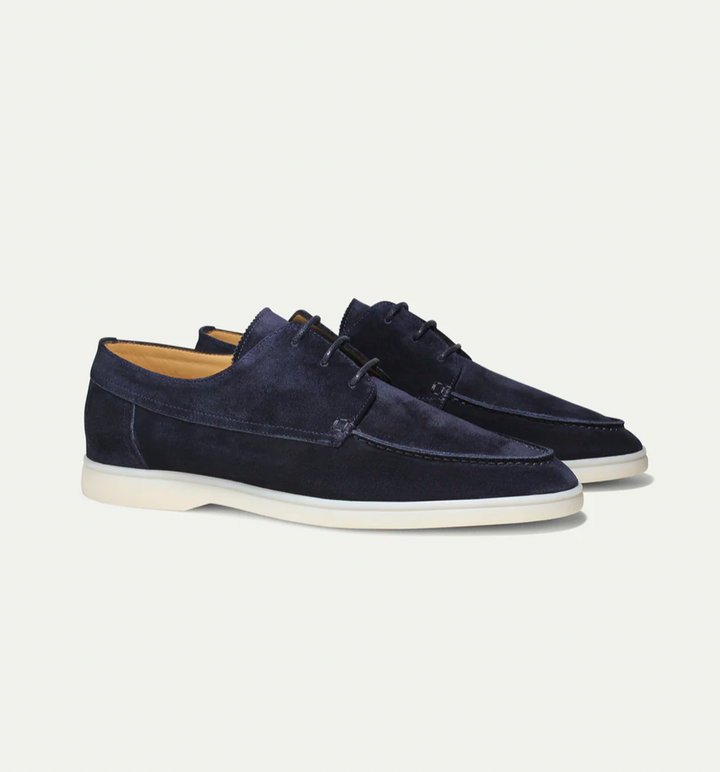 Dunkelblaue Herren-Schnürschuhe aus weichem Wildleder mit heller, leichter Sohle und klassischer Silhouette.