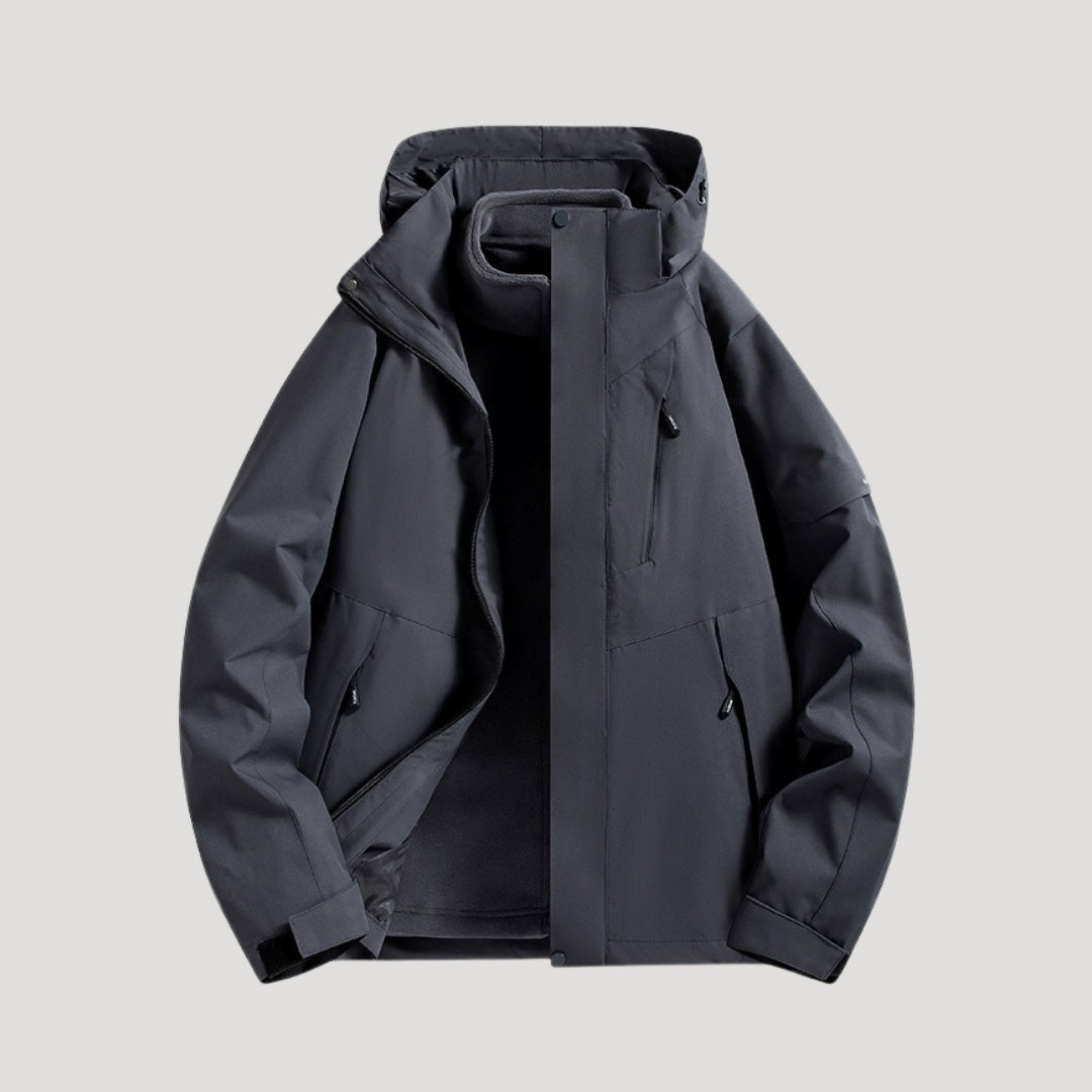 Dunkelgraue, wasserdichte Damen-Outdoorjacke mit Kapuze, Reißverschlusstaschen und sportlichem Design.