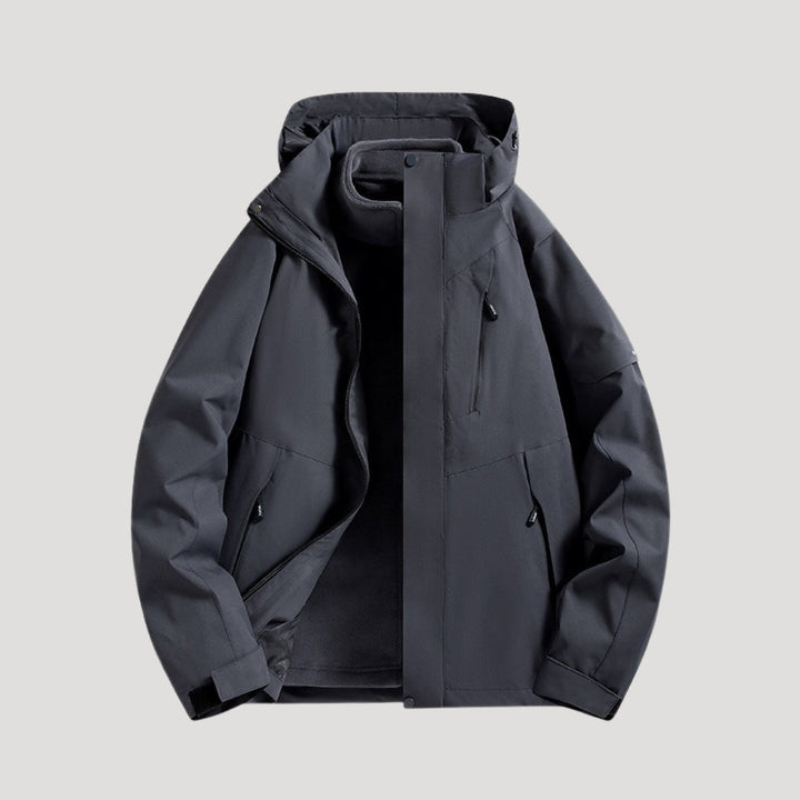 Dunkelgraue, wasserdichte Damen-Outdoorjacke mit Kapuze, Reißverschlusstaschen und sportlichem Design.