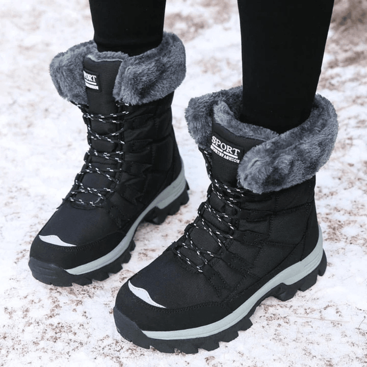 Schwarze Marika Winter-Snowboots mit Kunstfellkragen, Schnürung und profilierter Sohle auf Schnee.
