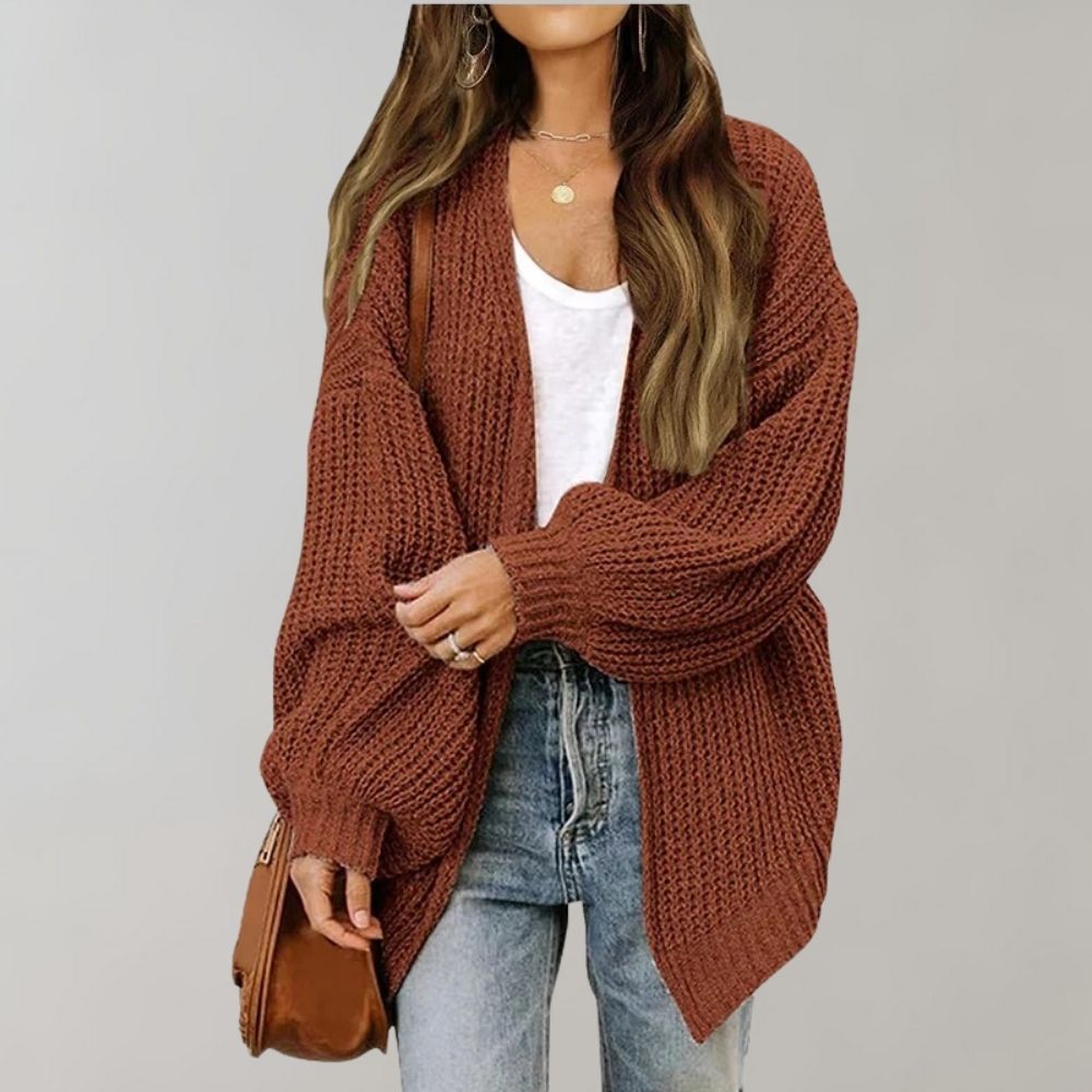 Rostbraune, offene Oversized-Strickjacke aus grobem Strick mit weiten Ärmeln kombiniert zu Jeans und weißem Top.