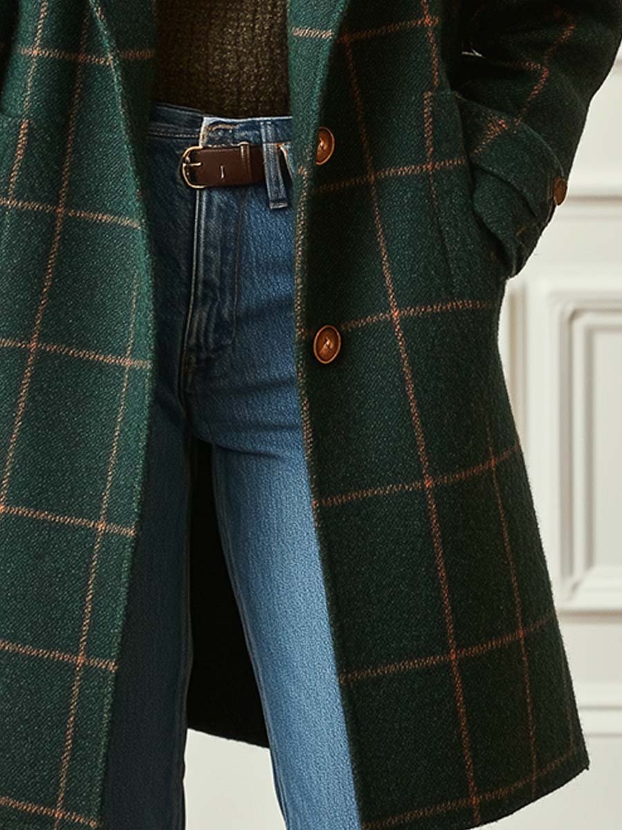 Dunkelgrüner karierter Wollmantel mit Reverskragen, Knopfleiste und Seitentaschen über blauer Jeans.