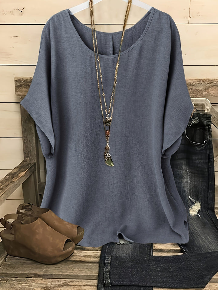 Blaues Damen-Kurzarmshirt in Leinen-Optik mit Rundhals und lockerer Passform, kombiniert mit Jeans und Sandalen.