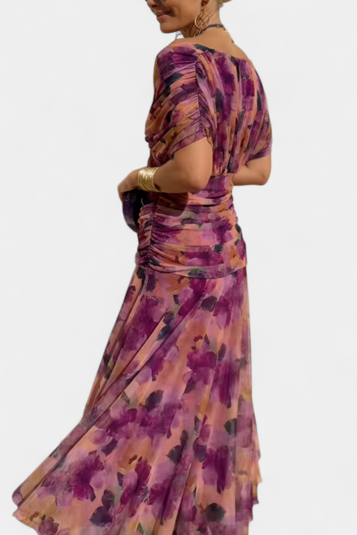 Langes, fließendes Maxikleid mit V-Ausschnitt, geraffter Taille und floralem Muster in Lila- und Rosatönen.