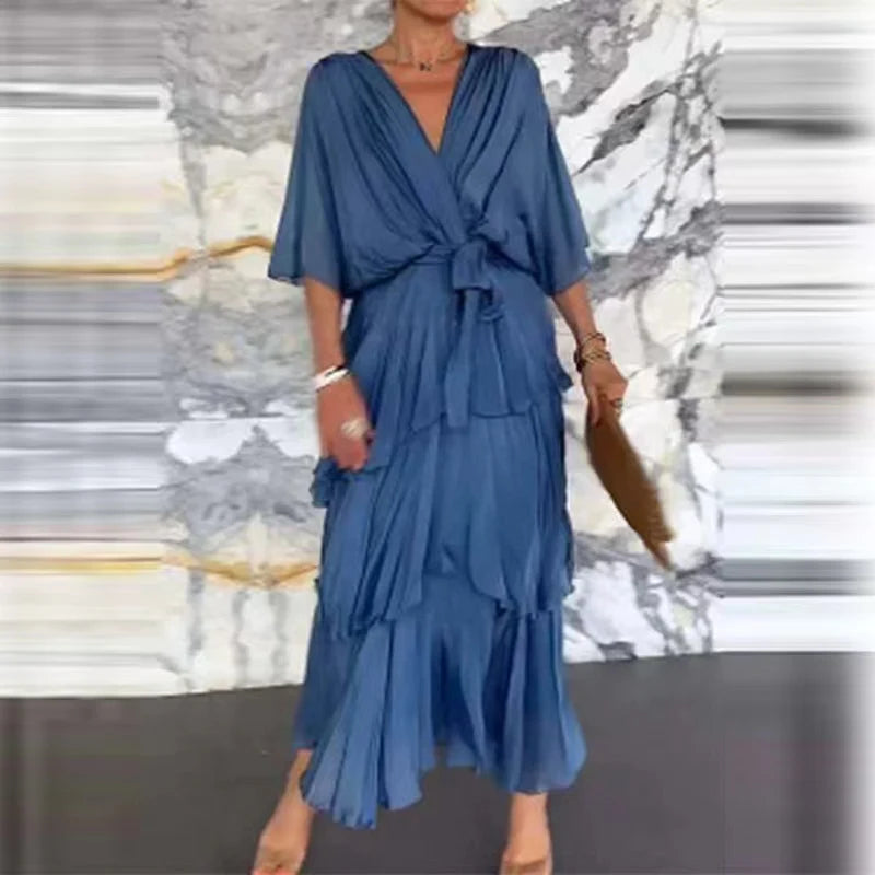 Blaues Midikleid mit V-Ausschnitt, Wickeloptik, Taillenbindung und gestuftem Rock aus fließendem Stoff.