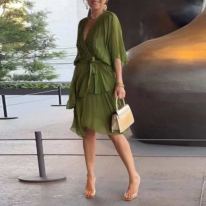Olivgrünes Midikleid mit V-Ausschnitt, Wickeloptik, Taillenbindung und gestuftem Rock in fließendem Stoff.