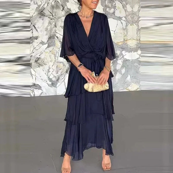 Dunkelblaues Midikleid mit V-Ausschnitt, Wickeloptik, Taillenband und gestuftem Rock aus fließendem Stoff.