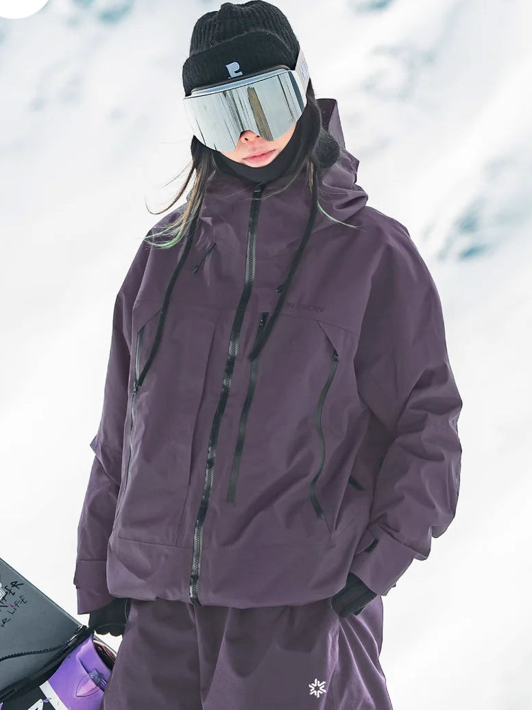 Dunkelviolette, wasserdichte Damen-Skijacke mit Kapuze, Reißverschlusstaschen und lockerem Schnitt im Schnee.