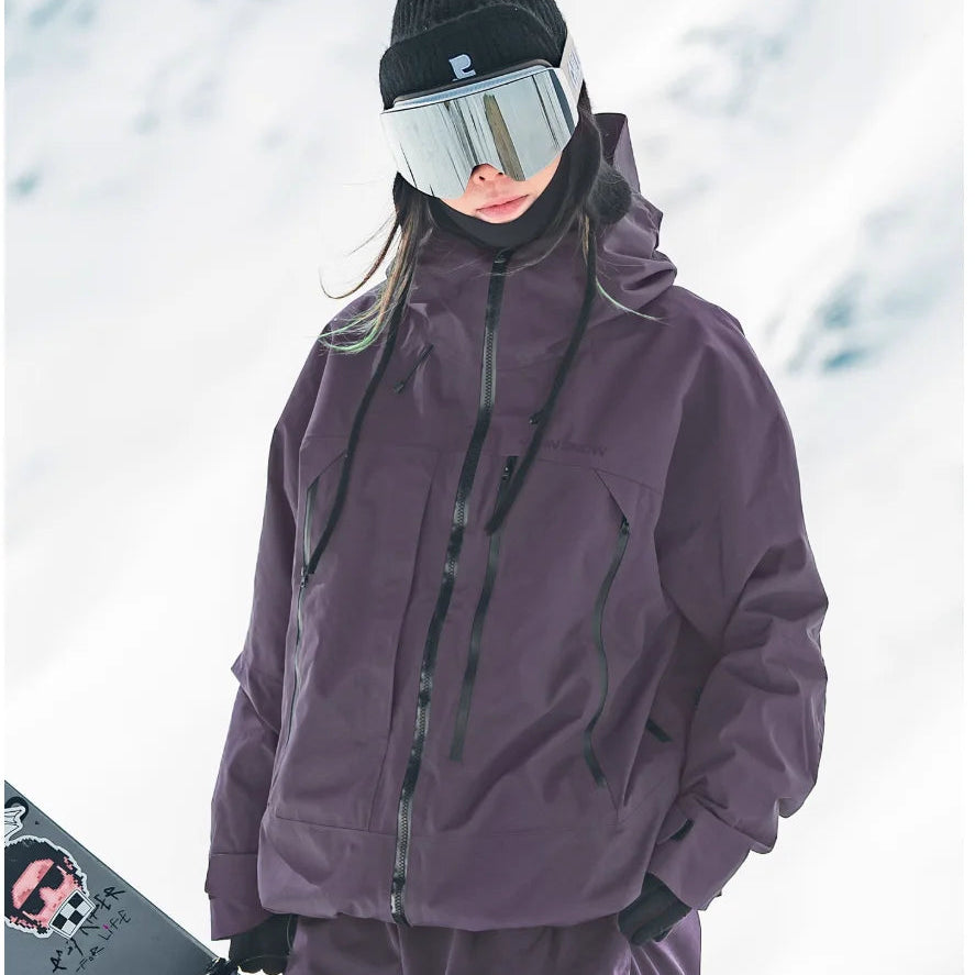 Dunkellila wasserdichte Damen-Skijacke mit Kapuze und Reißverschlusstaschen im lockeren Schnitt im Schnee.