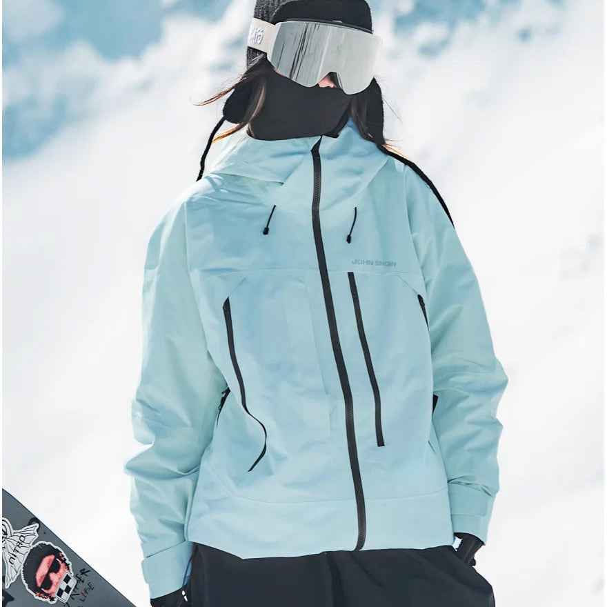 Hellblaue, wasserdichte Damen-Skijacke Melina mit Kapuze, schwarzen Reißverschlüssen und lockerem Schnitt im Schnee.