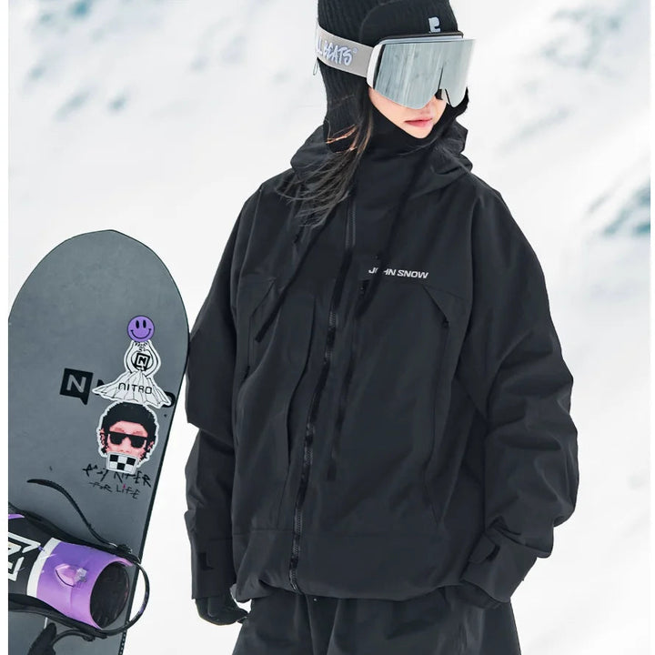 Schwarze, wasserdichte Melina Damen-Skijacke mit Kapuze und Reißverschluss, getragen beim Snowboarden im Schnee.