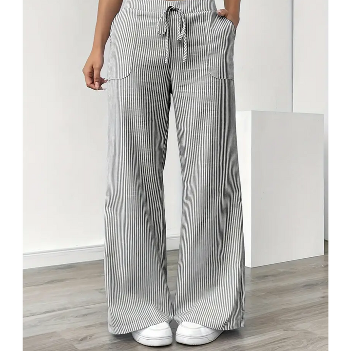 Weite Leinenhose mit vertikalen Streifen, Kordelzug am Bund und aufgesetzten Seitentaschen in Grau und Weiß.