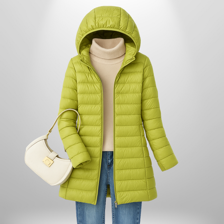 Taillierte, lindgrüne Milena Daunenjacke mit Kapuze, kombiniert mit beigem Rollkragenpullover und Jeans.