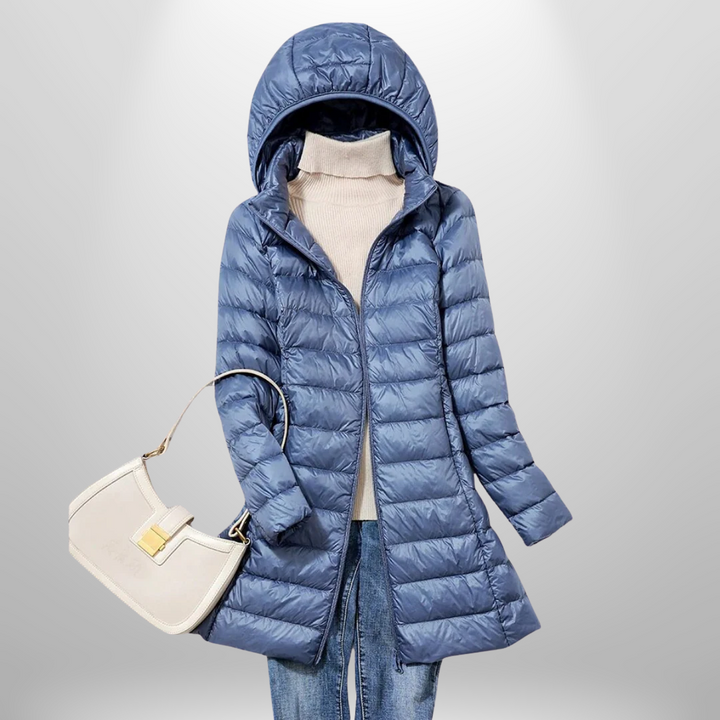 Taillierte, blaue Milena Daunenjacke mit Kapuze, kombiniert mit beigem Rollkragenpullover und weißer Handtasche.