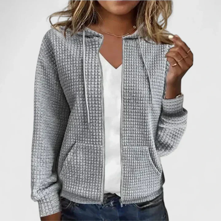 Graue Damen-Steppjacke mit Waffelstruktur, Kapuze, Kordelzug und durchgehendem Reißverschluss.
