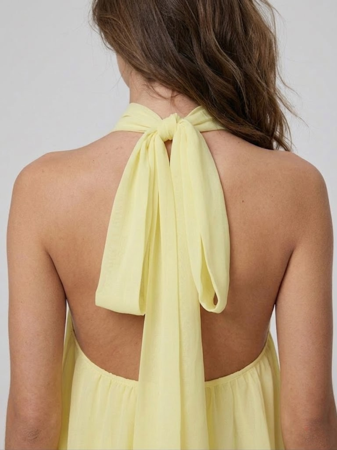 Hellgelbes Mira Minikleid mit Neckholder-Bindeband und offenem Rückenausschnitt aus leichtem, fließendem Stoff.