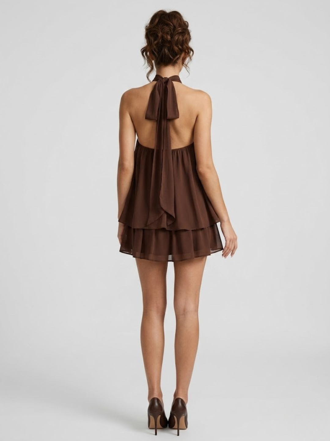 Braunes Neckholder-Minikleid mit offenem Rücken, stufigen Volants und fließendem Stoff.