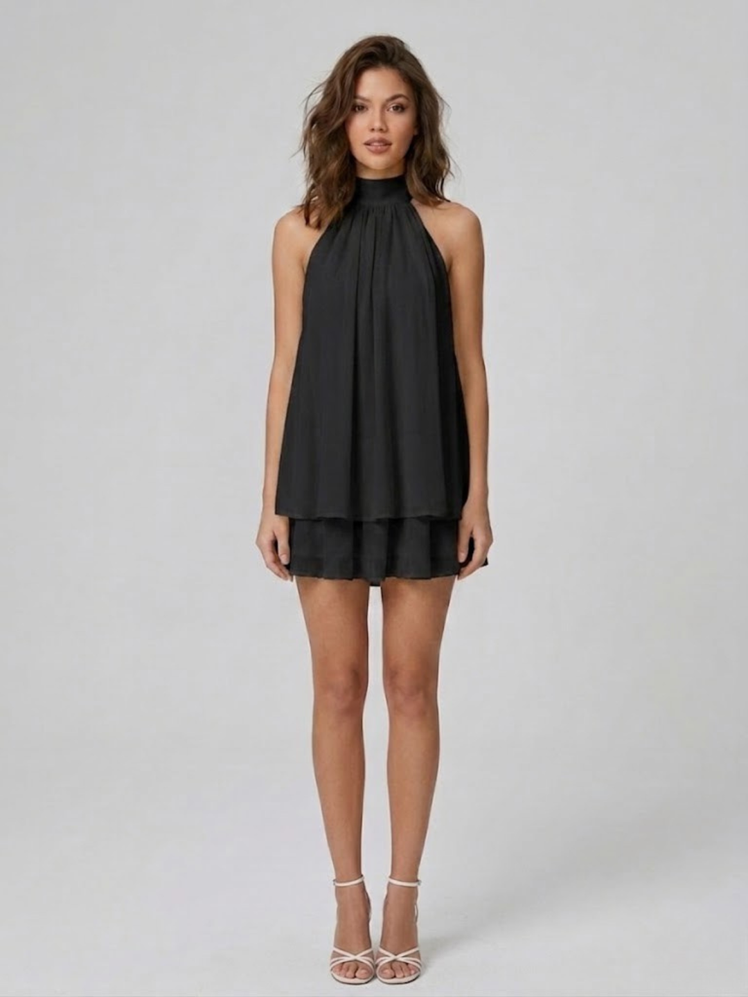 Schwarzes Neckholder-Minikleid mit fließendem Stoff und verspielten Volants für einen eleganten Sommer-Look.