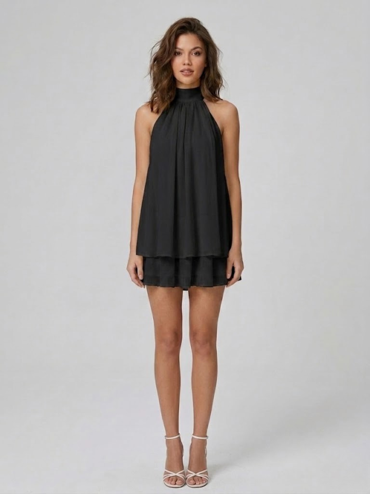 Schwarzes Neckholder-Minikleid mit fließendem Stoff und verspielten Volants für einen eleganten Sommer-Look.