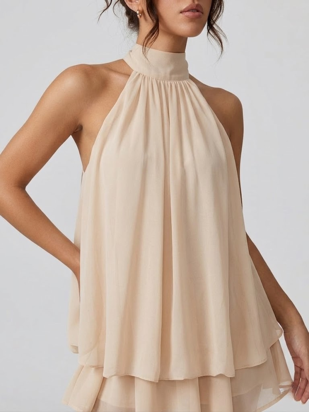 Beiges Mira Minikleid mit Neckholder-Ausschnitt, fließendem Stoff und verspielten Volant-Details für den Sommer.