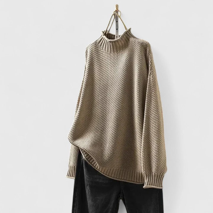 Beiger Damen-Strickpullover mit Stehkragen, strukturiertem Muster und entspannter Passform an einem Kleiderbügel.