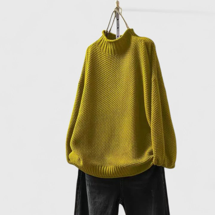 Senfgelber Strickpullover mit Stehkragen, strukturiertem Muster und entspannter Passform an einem Kleiderbügel.
