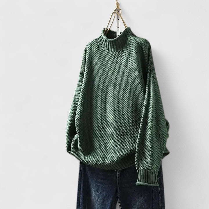 Grüner Damen-Strickpullover mit Stehkragen, strukturiertem Strickmuster und entspannter Passform an einem Kleiderbügel.