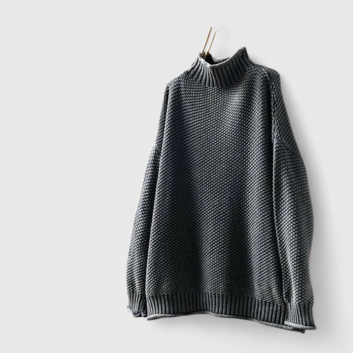 Dunkelgrauer Damen-Strickpullover mit Stehkragen, strukturiertem Muster und entspannter Passform an einem Kleiderbügel.