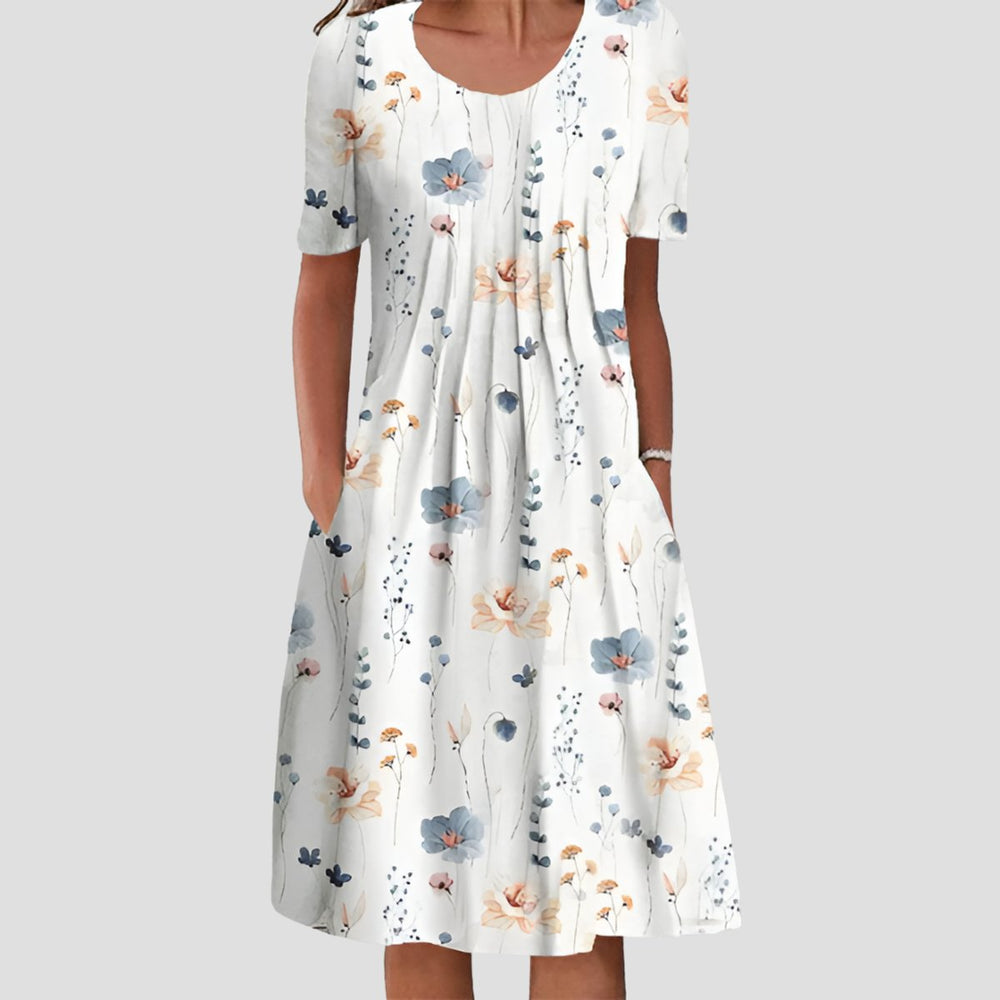 Weißes Midikleid mit Blumenmuster, Rundhalsausschnitt, kurzen Ärmeln und praktischen Seitentaschen im A-Linien-Schnitt.