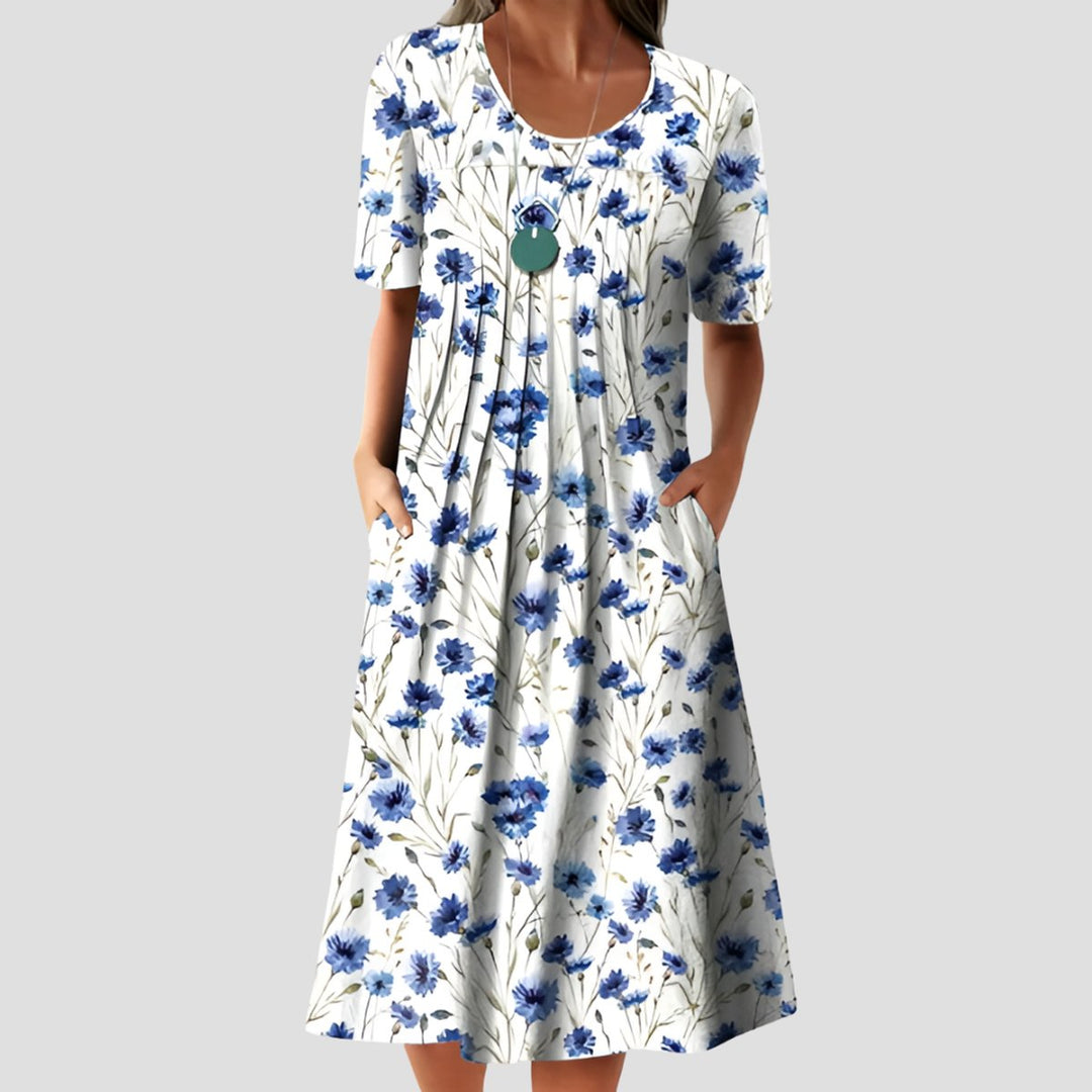 Weißes Midikleid mit blauem Blumenmuster, A-Linien-Schnitt, Rundhalsausschnitt, kurzen Ärmeln und praktischen Seitentaschen.