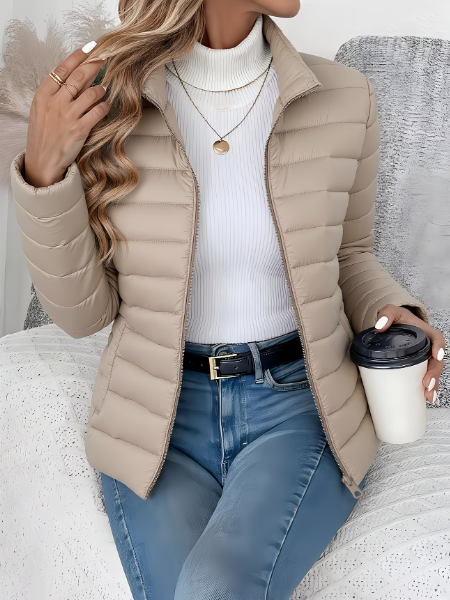 Beigefarbene, taillierte Damen-Steppjacke mit Stehkragen und Reißverschluss für die Übergangszeit.