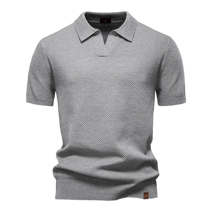 Graues Herren-Poloshirt mit feiner Struktur, offenem Kragen, kurzen Ärmeln und moderner Passform.
