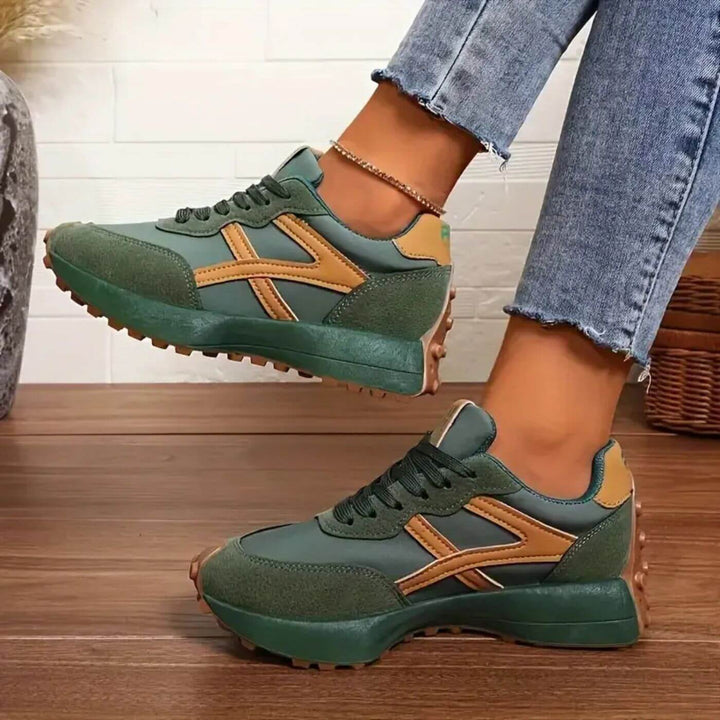Damen Retro-Sneaker in Dunkelgrün mit braunen Kontraststreifen, Schnürung und markanter, profilierter Laufsohle.