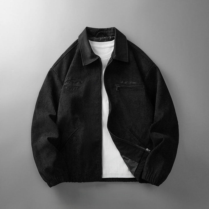 Schwarze Herren-Cordjacke mit Reißverschluss, Umlegekragen, Brusttasche und elastischem Saum über weißem T-Shirt.