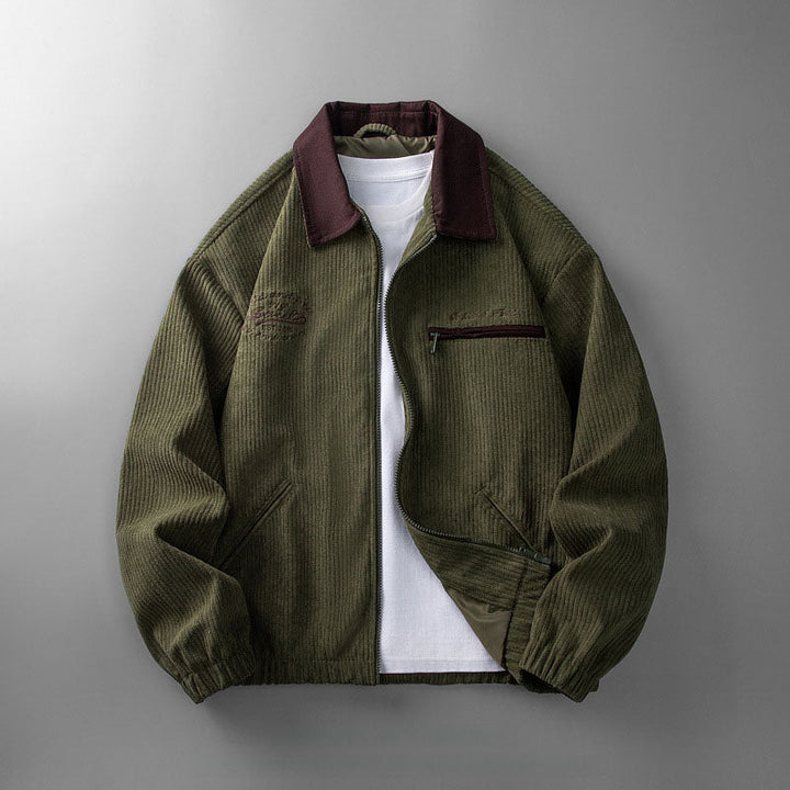 Olivgrüne Herren-Cordjacke mit Reißverschluss, dunkelrotem Kragen, Brusttasche und elastischem Saum über weißem Shirt.